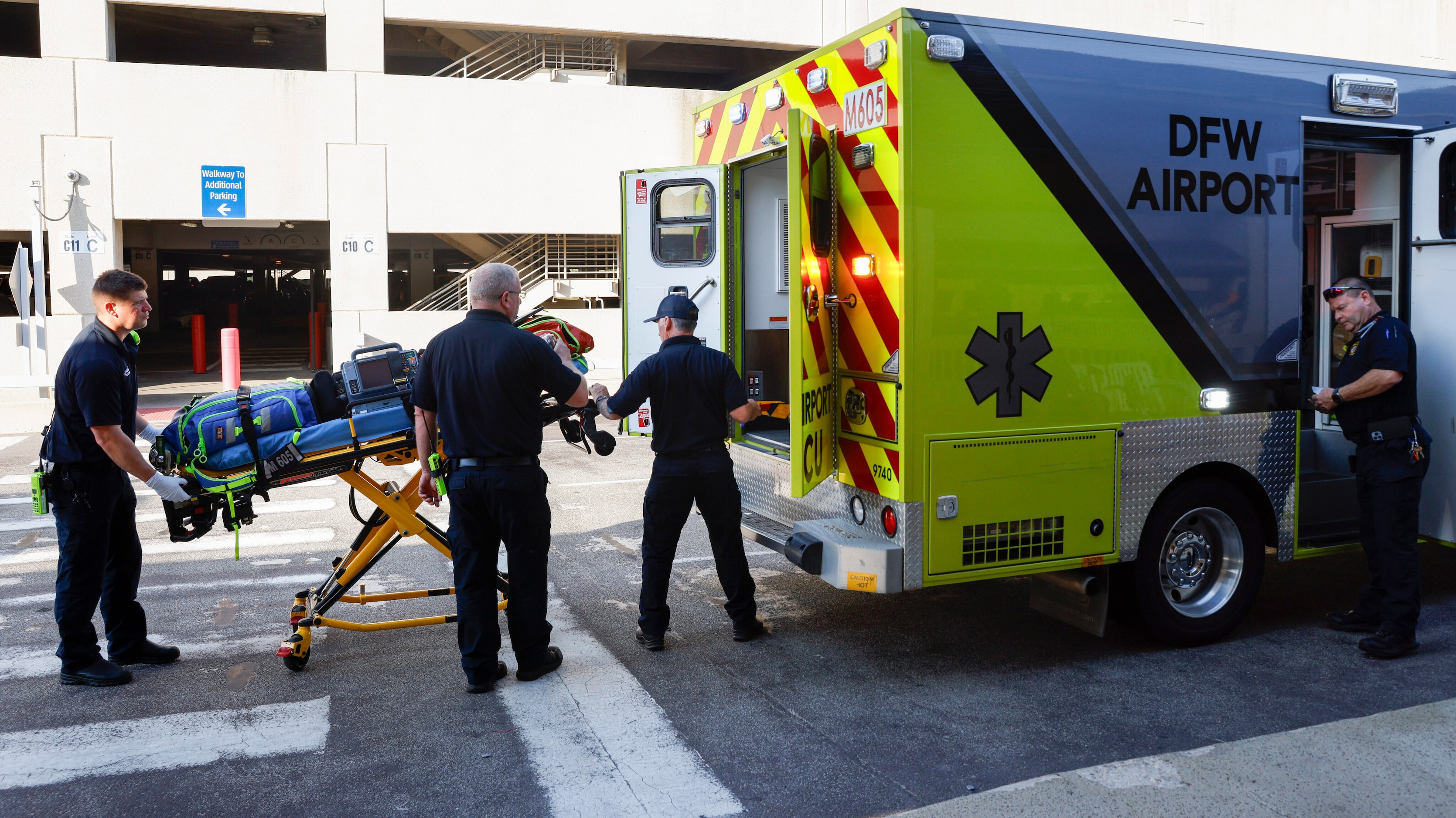 DFW Airport Fire Department firefighters and paramedics load a stretcher into the back of an...