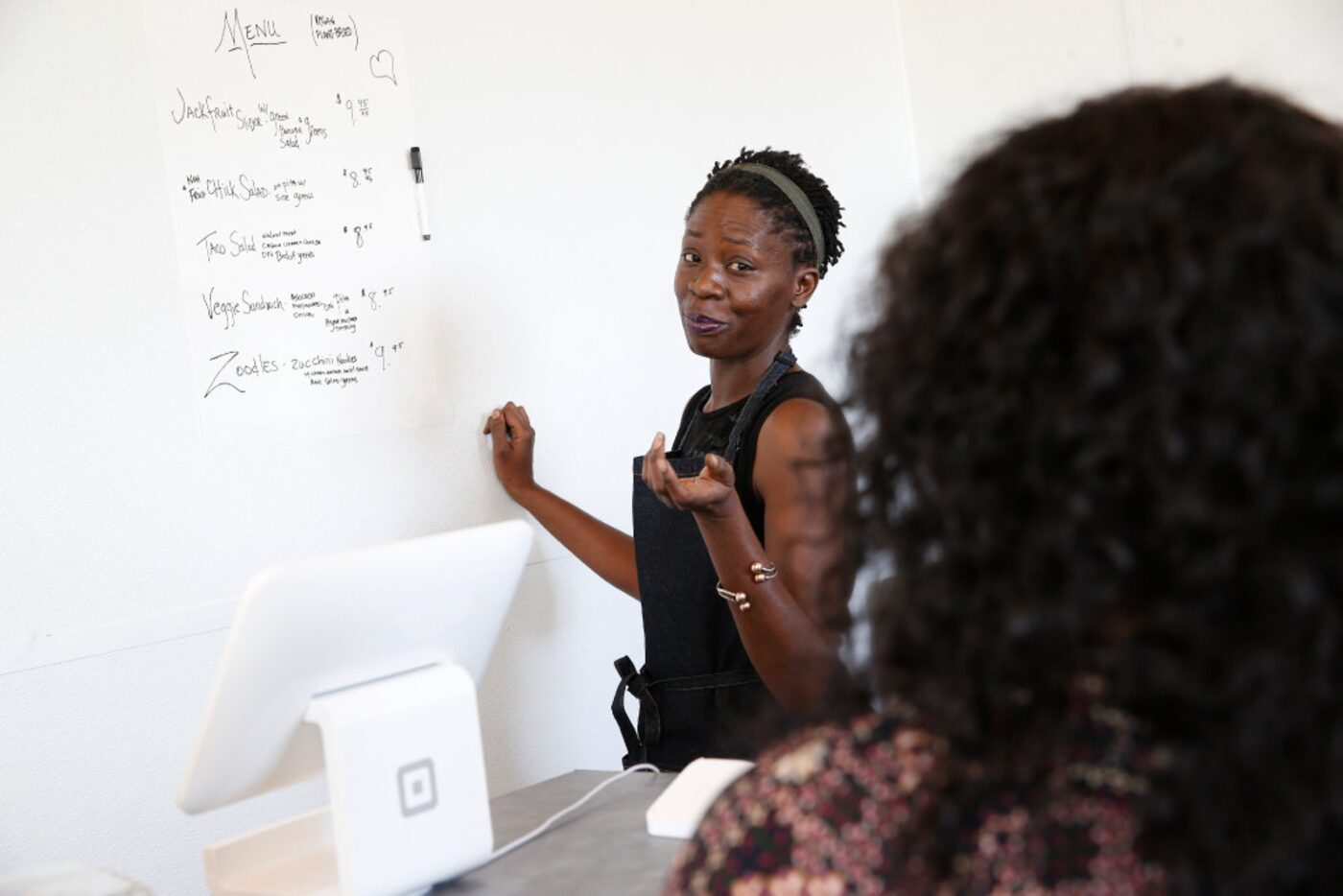 Tisha Crear goes over the menu with a customer at her vegan restaurant, Recipe.