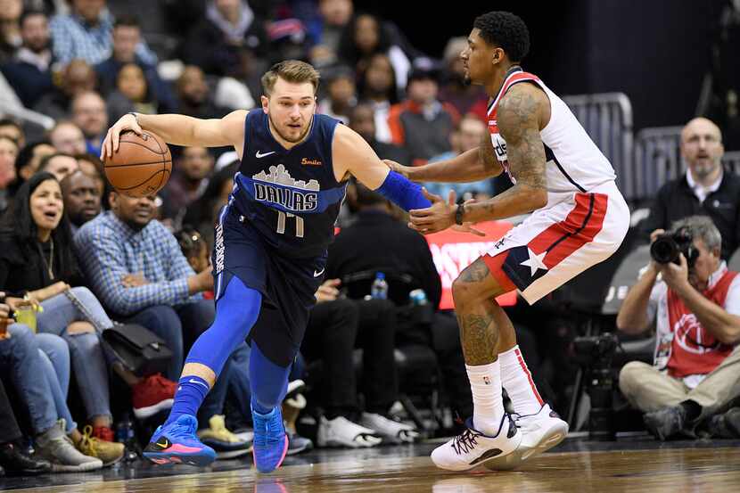 Dallas Mavericks forward Luka Doncic (77) dribbles the ball next to Washington Wizards guard...