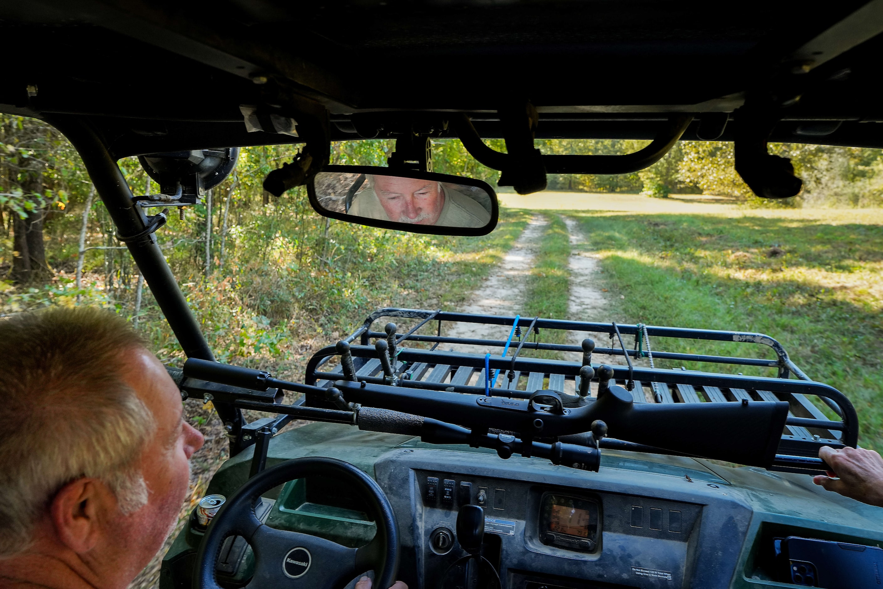 With a hunting rifle handy on their Kawasaki Mule, Bill & Joyce Wilson drive through their...