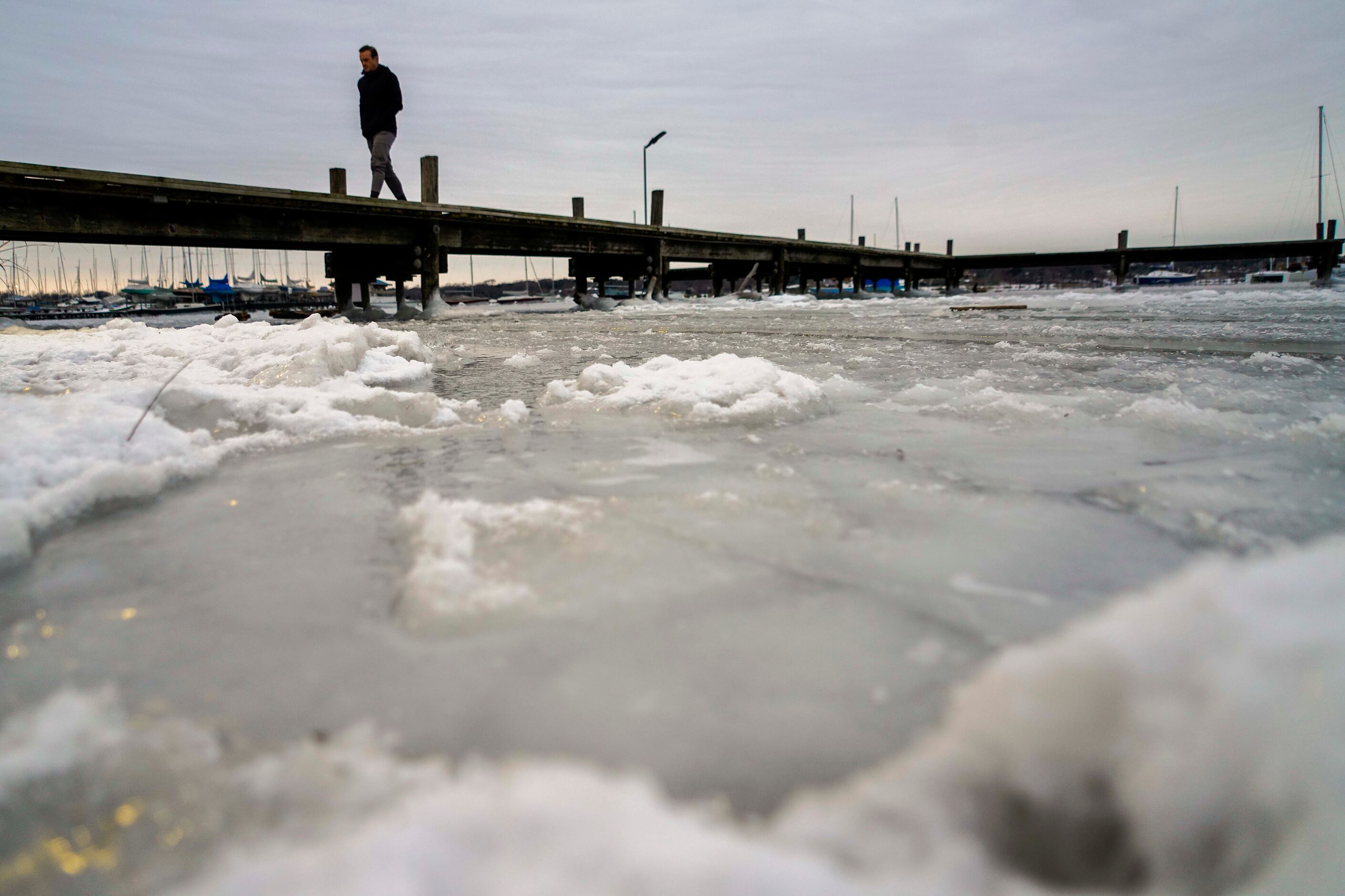 Frozen waters of White Rock Lake surround a pier after a winter storm brought snow and...