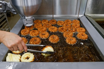 Crullers fry at La Rue Doughnuts in Trinity Groves. Once done, they're glazed or frosted....