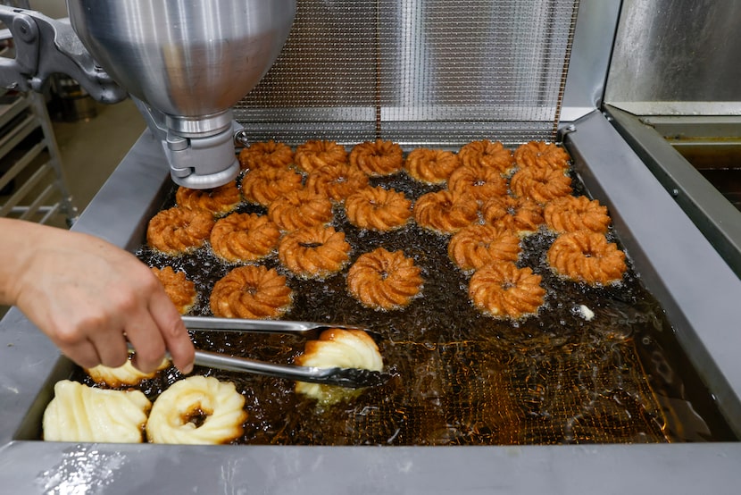 An employee flips crullers as they fry at La Rue Doughnuts in Trinity Groves, Wednesday,...