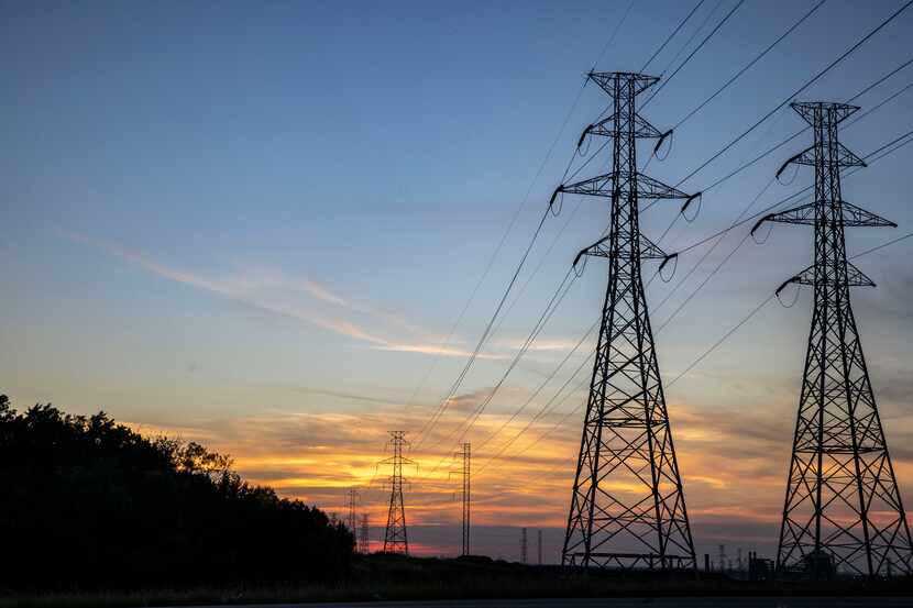 The sun sets behind electricity towers along Mountain Creek Parkway in Dallas on Wednesday,...
