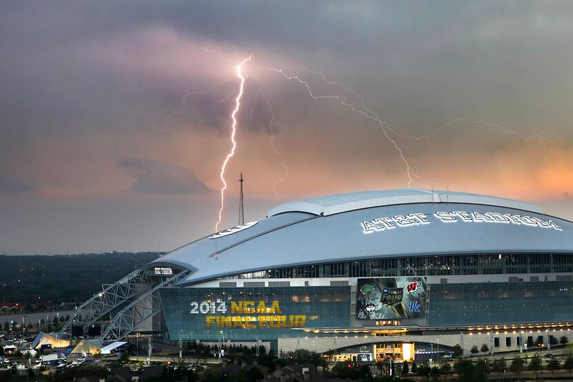 A lightning bolt from a passing thunderstorm strikes in the distance far behind AT&T Stadium...