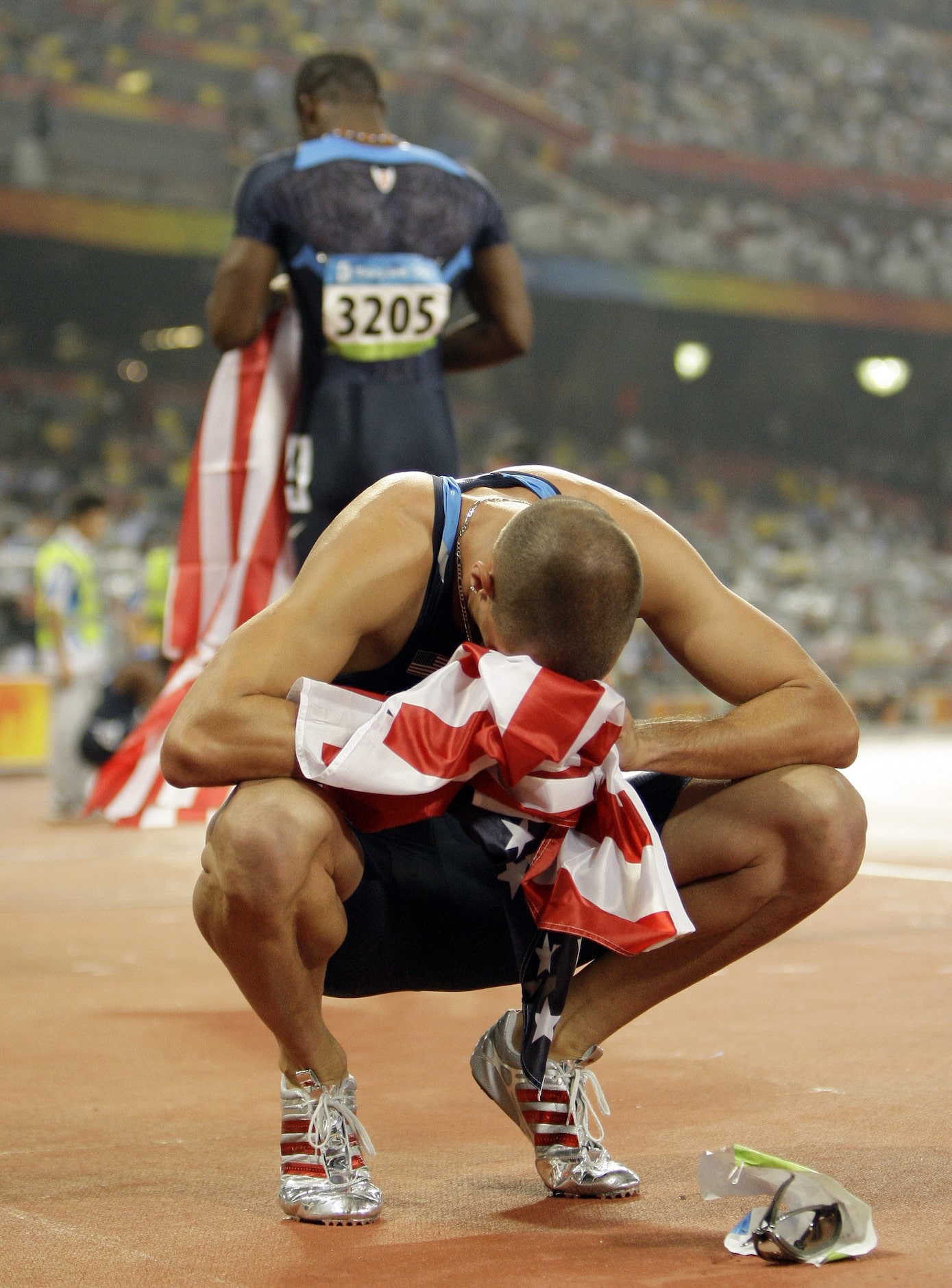 2008 Beijing Olympics: Jeremy Wariner puts his head in a U. S. flag given to him by LaShawn...