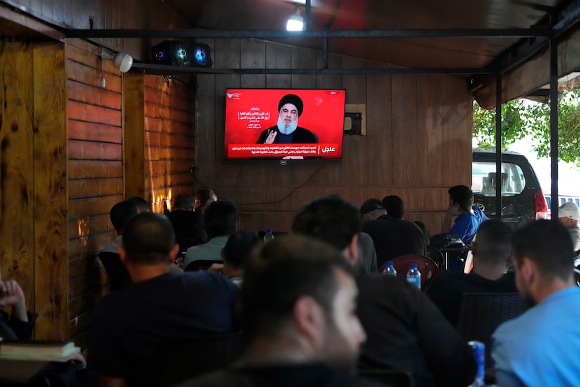 People watch the speech of Hezbollah leader Hassan Nasrallah on a tv screen as they sit in a...