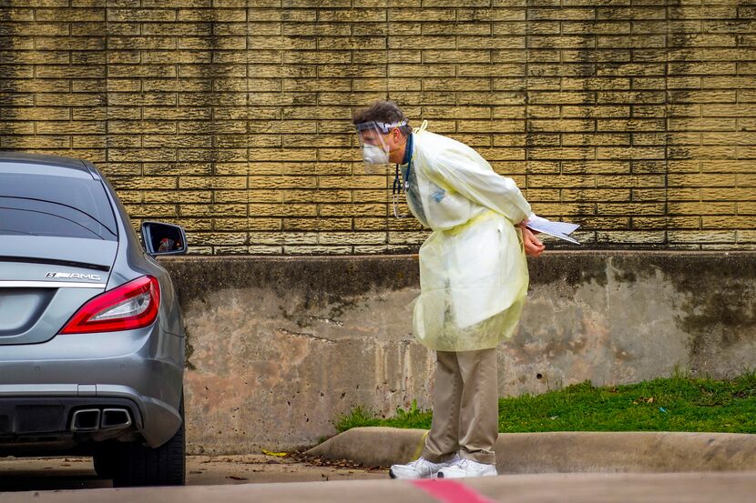 Dr. Martin McElya kept his distance as he talked with a patient during drive-through...