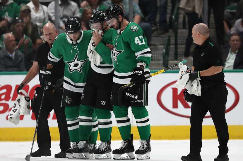 Blake Comeau #15 of the Dallas Stars is helped off the ice after a puck hit him in the face...