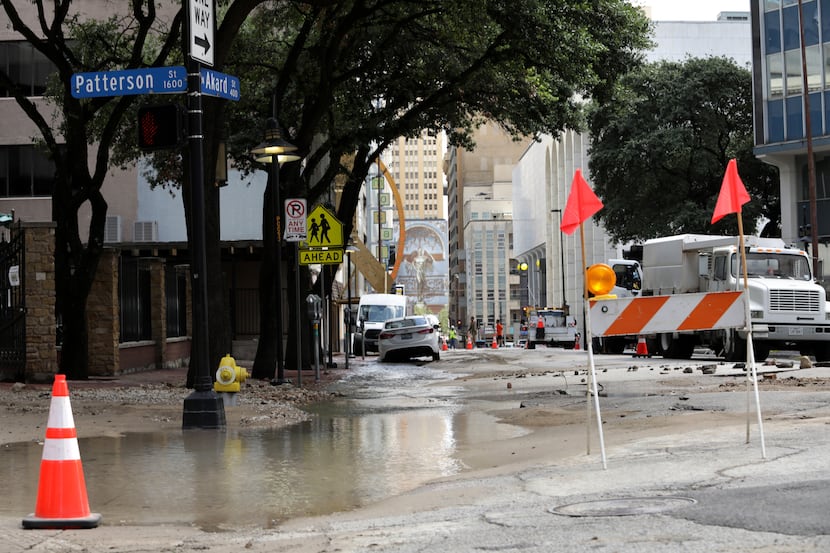 Workers secure an area damaged by a water main break at Akard Street and Patterson Street in...