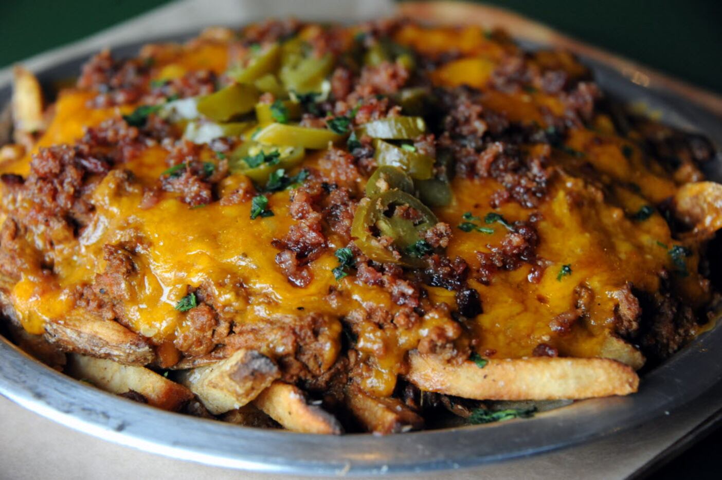 The cheese fries surprise are hand punched fries with parsley, cheddar, and house made chili...