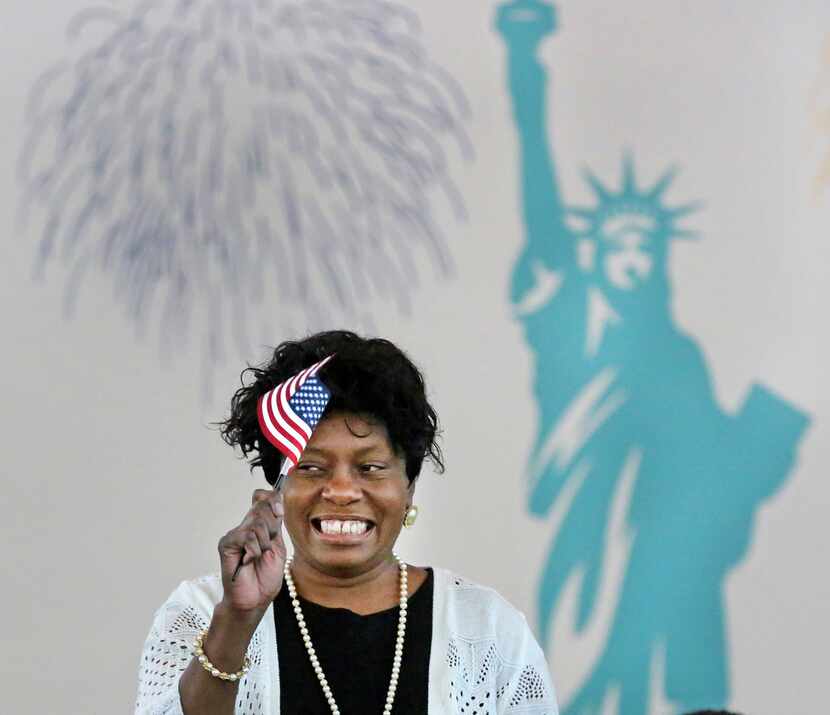 Elizabeth Evans, from Zambia, happily waves a miniature American flag as she becomes an...