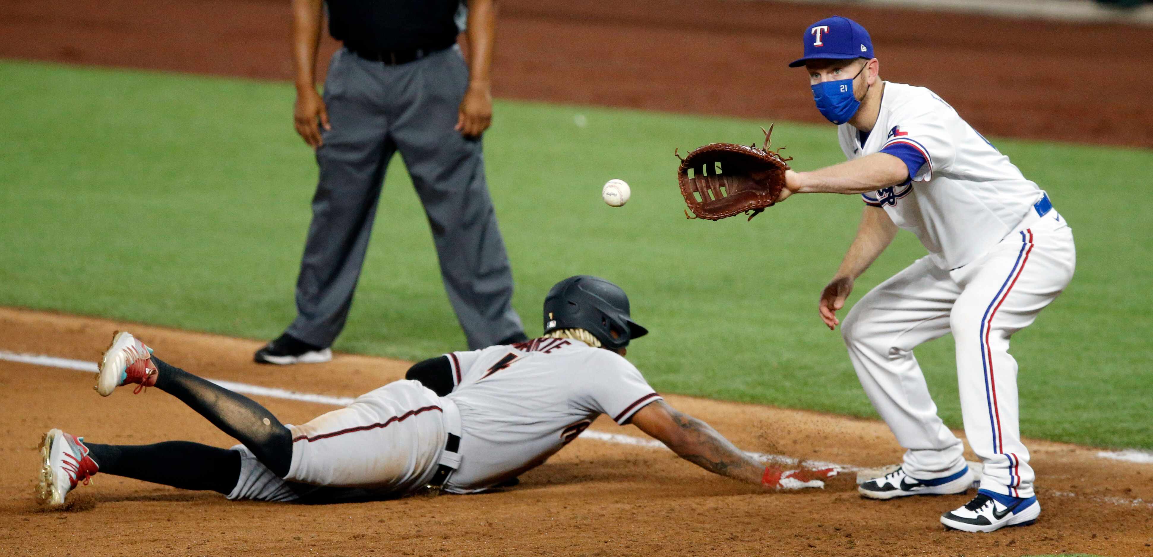 Arizona Diamondbacks Ketel Marte (4) dives back to first ahead of the throw to Texas Rangers...