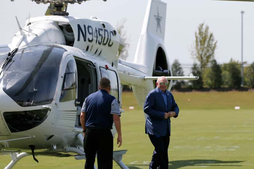Dallas Cowboys team owner Jerry Jones, right, walks off his customized helicopter after...