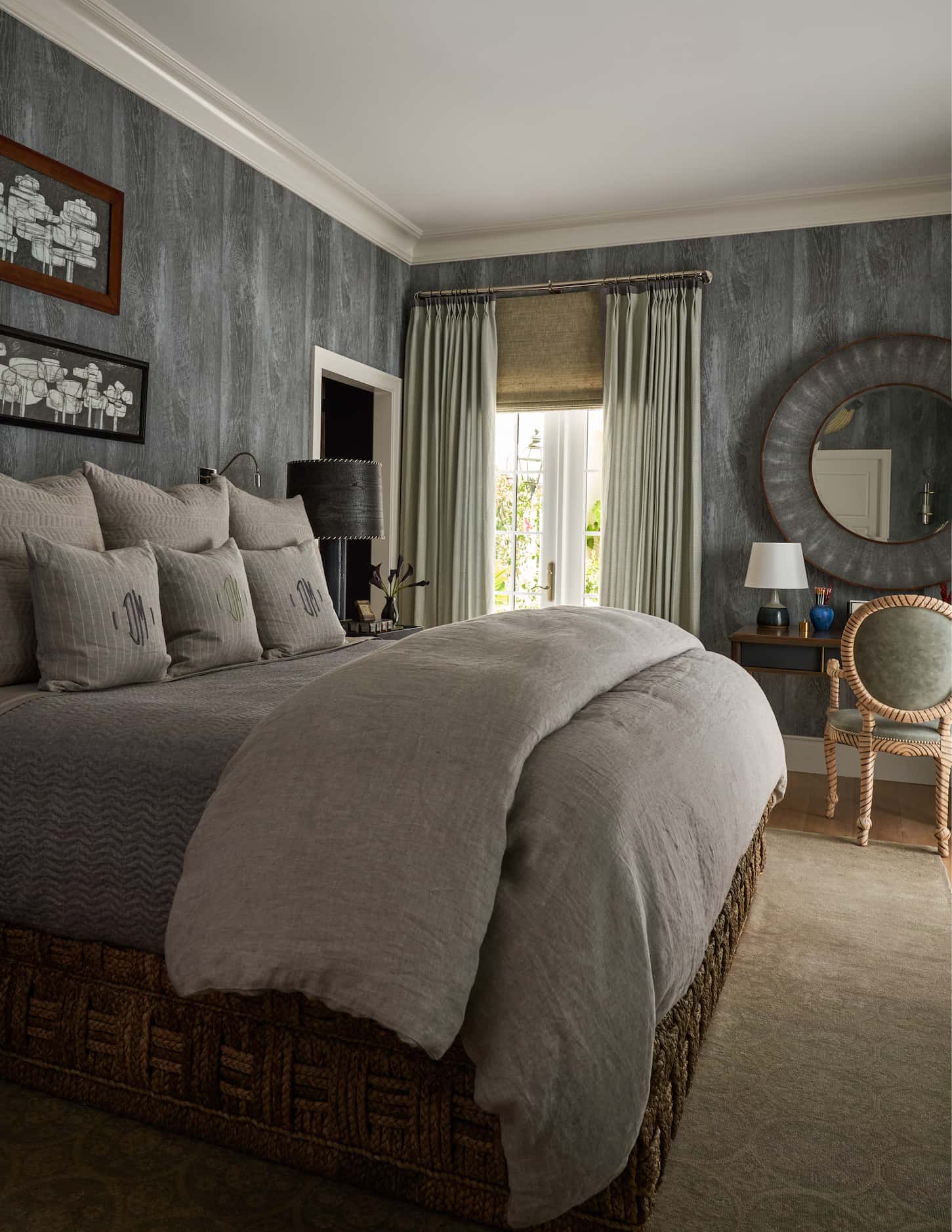 Bedroom with gray driftwood wallpaper, bed with neutral linens, desk and chair in background