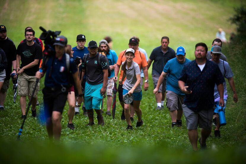 Professional disc golfer Paige Pierce, center right, walks with a crowd of fans and fellow...