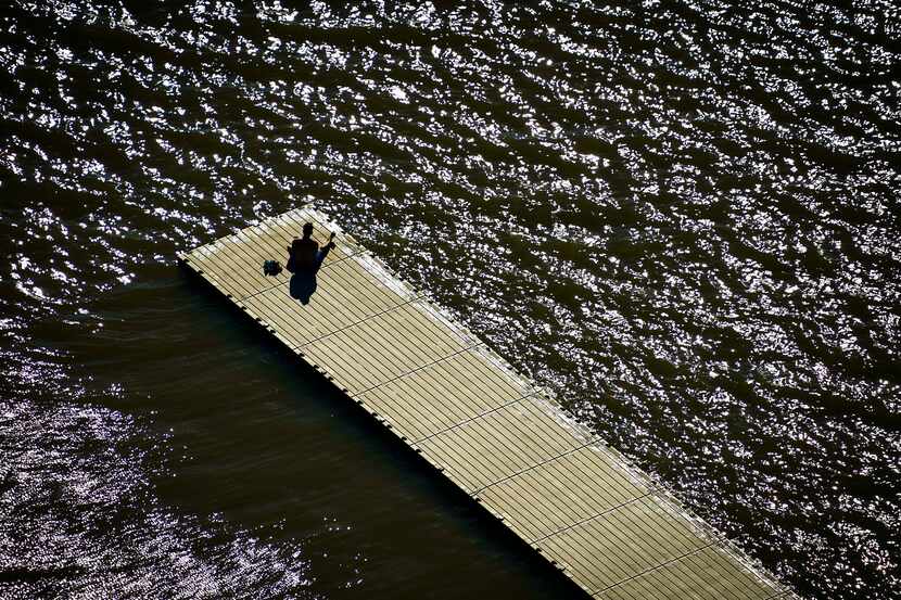 A solitary man sits on a dock at White Rock Lake in Dallas on Tuesday, March 24, 2020.