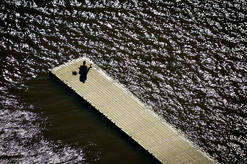 A solitary man sits on a dock at White Rock Lake in Dallas on Tuesday, March 24, 2020.