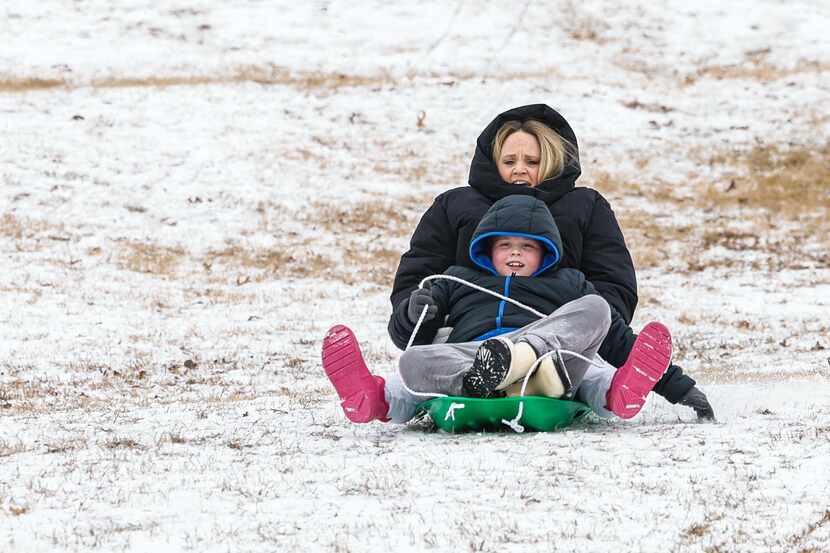 Laura Baines with her son Gus Baines slide together over the snow at Flag Pole Hill Park in...
