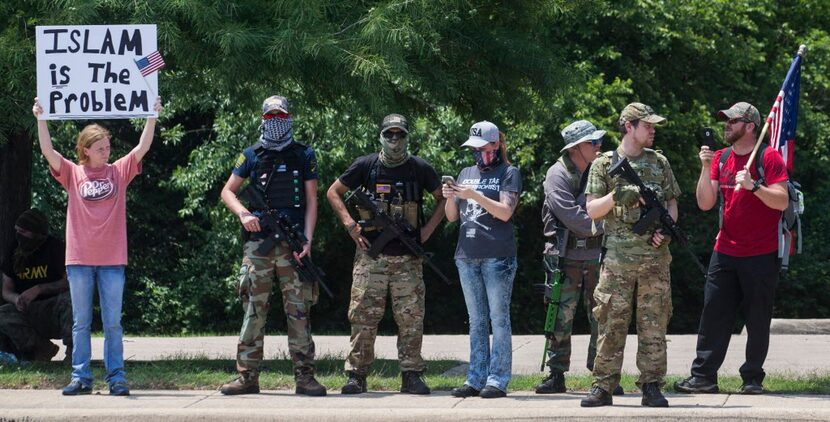 Anti-Shariah protesters stand at the intersection of Abrams Road and Centennial Boulevard...