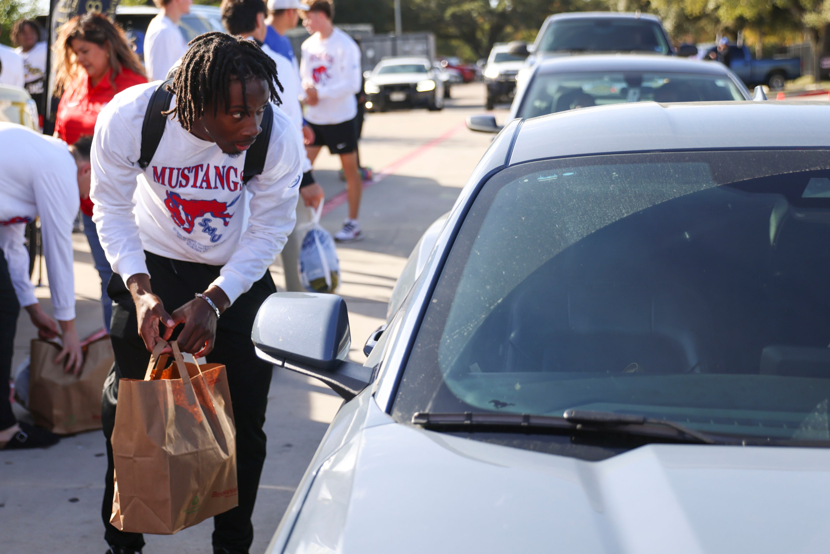 Southern Methodist University QB Kevin Jennings hands out turkeys and other goods on,...