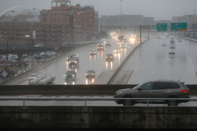 A car passes on St. Paul Street over Woodall Rodgers Freeway on a cold, rainy morning in...