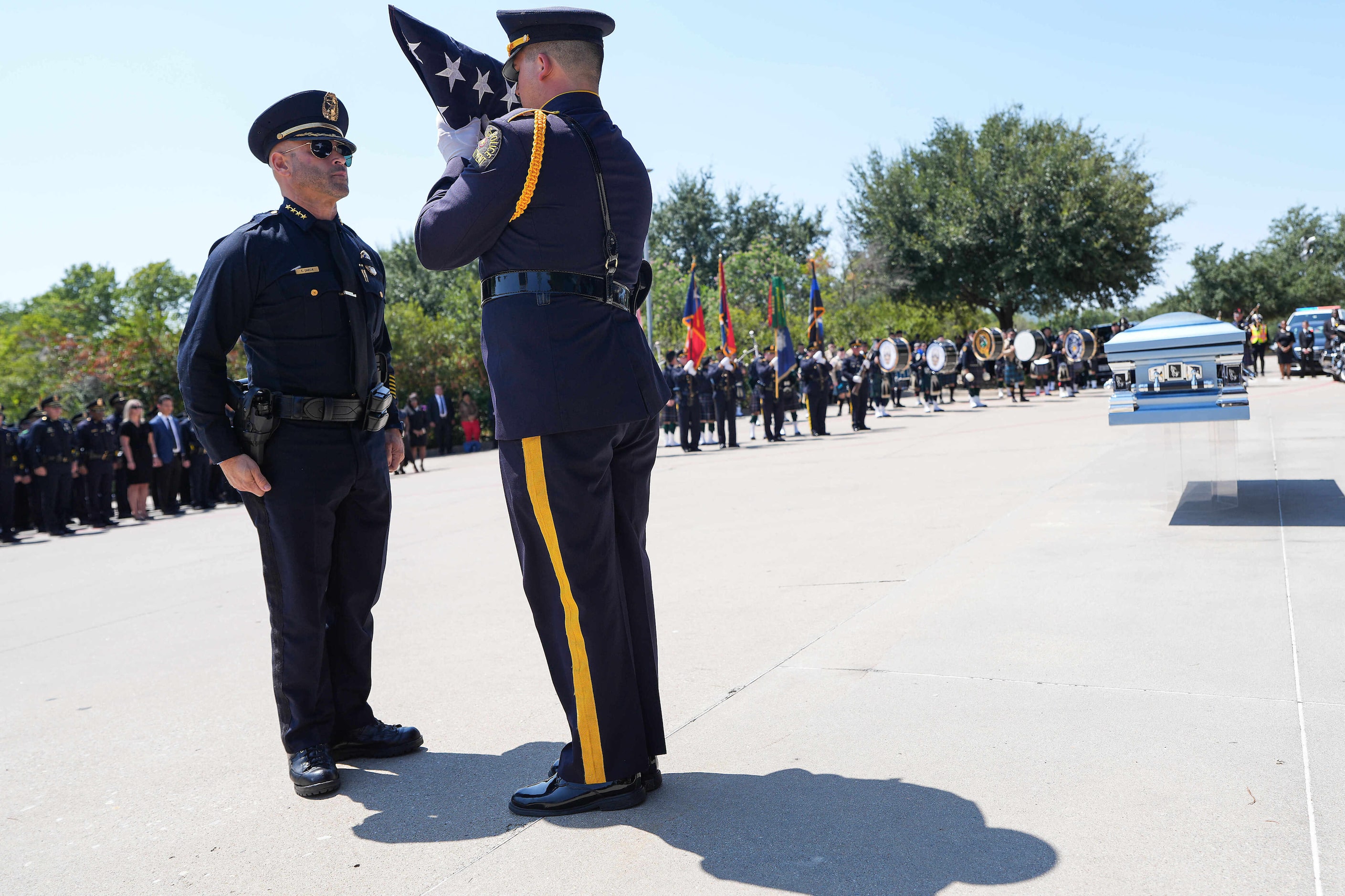 A member of the Dallas Police Honor Guard  transfers the folded flag from the casket of...