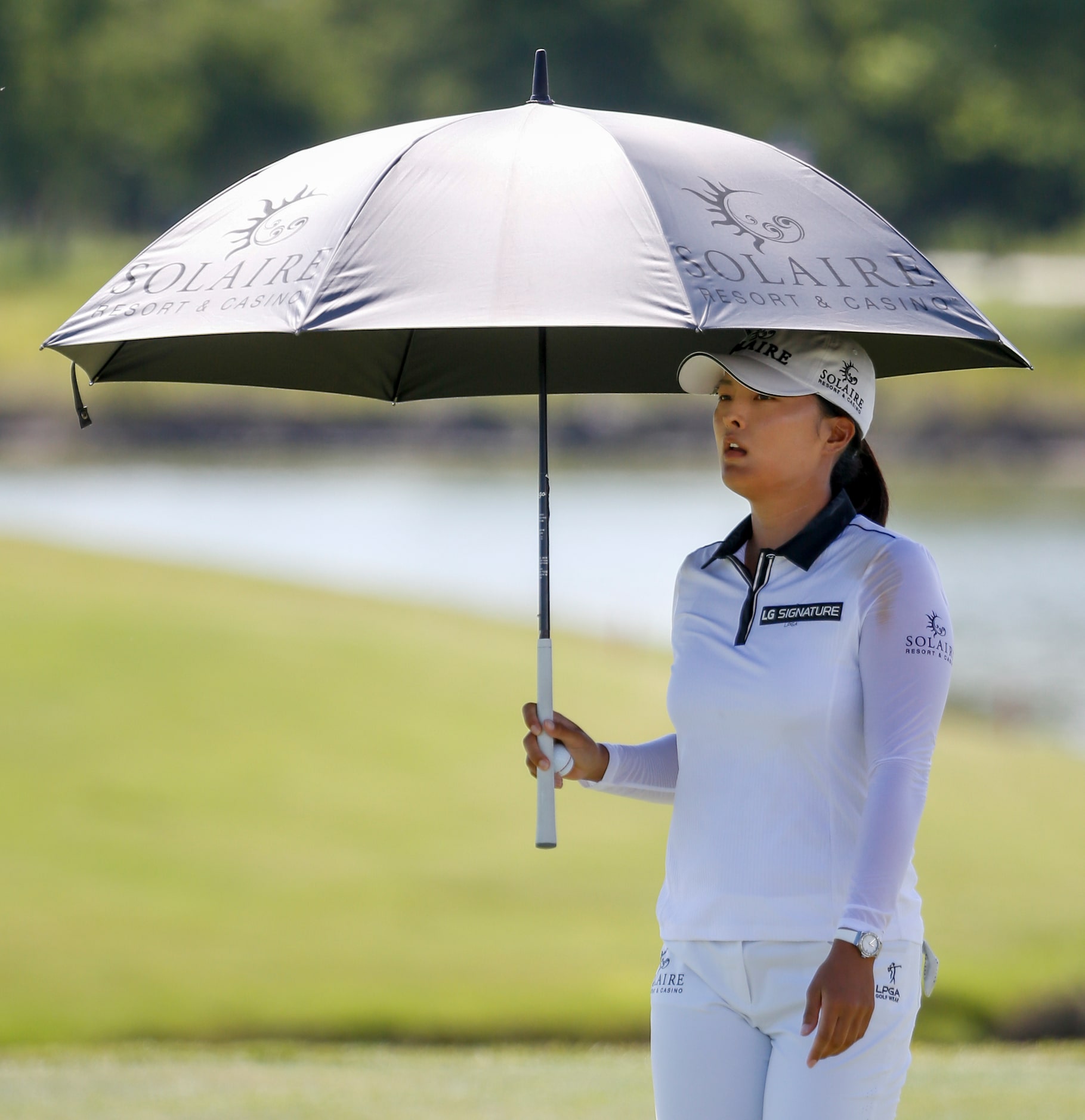 Professional golfer Jin Young Ko avoids the sun with an umbrella on the 18th green during...