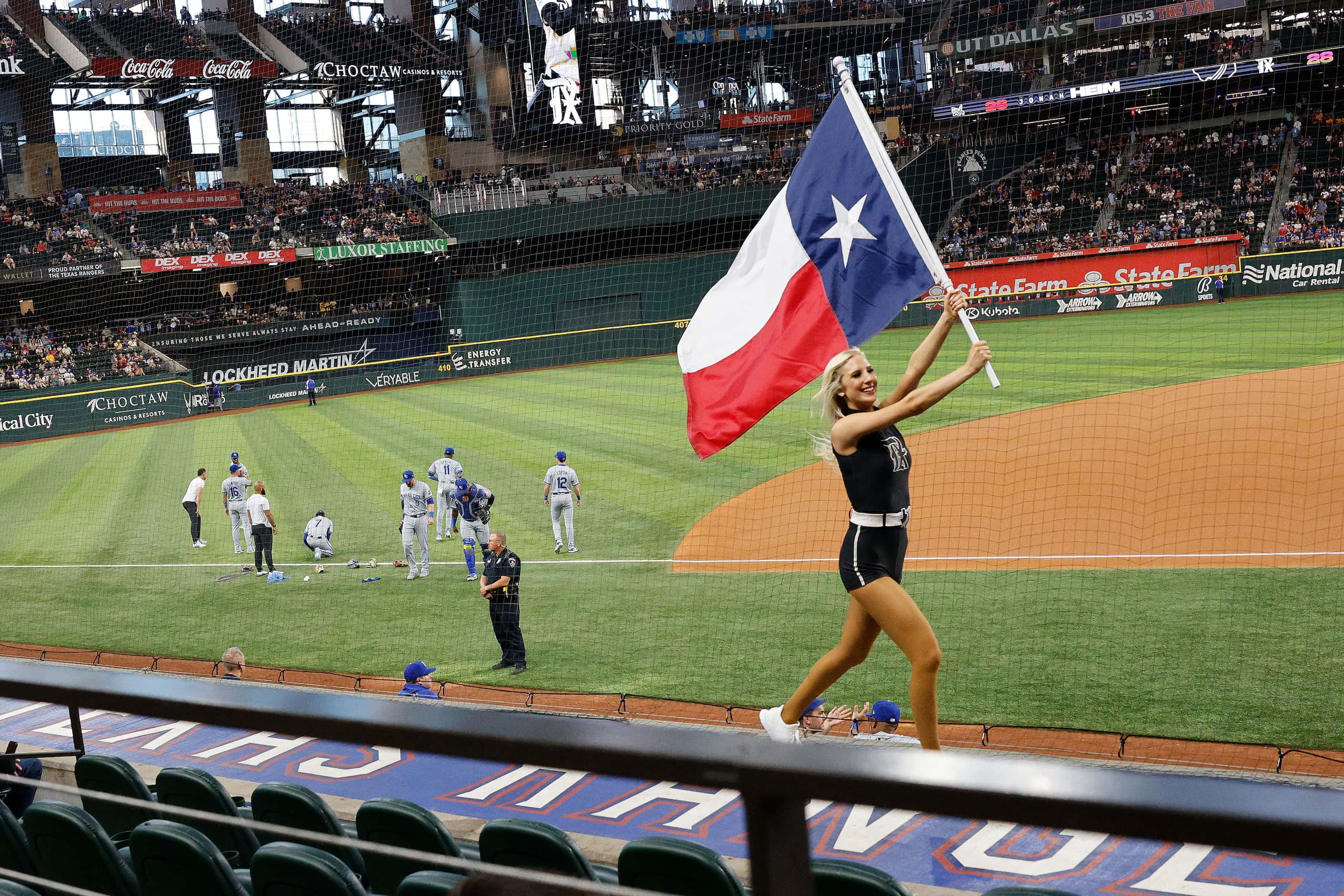A member of the Texas Rangers Six Shooters Squad runs with a Texas flag before a baseball...