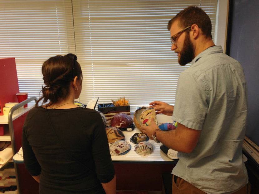 John Oberly shows art teacher Laura Hanel the masks his poetry students are working on for a...