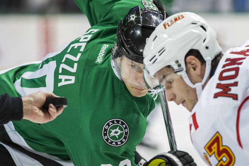 Dallas Stars center Jason Spezza (90) eyes the puck as he faces off against Calgary Flames...