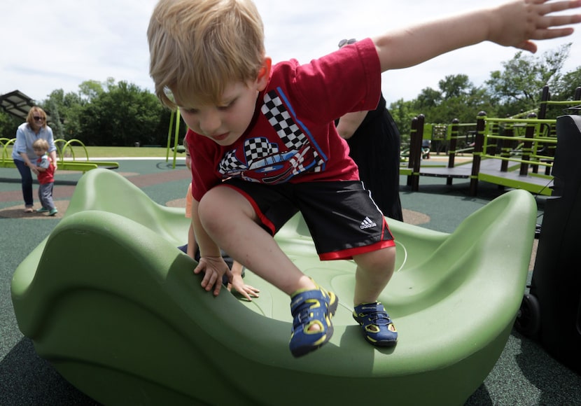 Four-year-old Quentin Reitzell plays on a merry-go-round that sits low to the ground in...