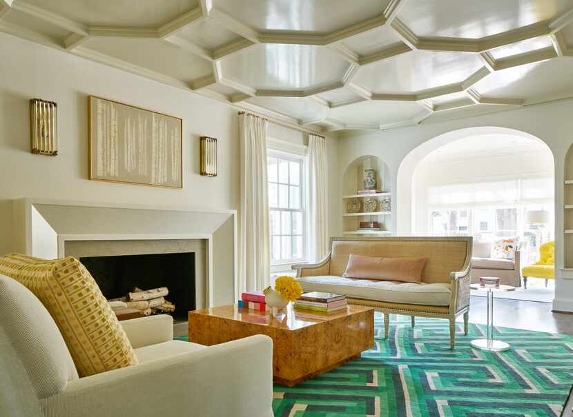 A living room features an emerald green carpet, white upholstered furniture, and modern...