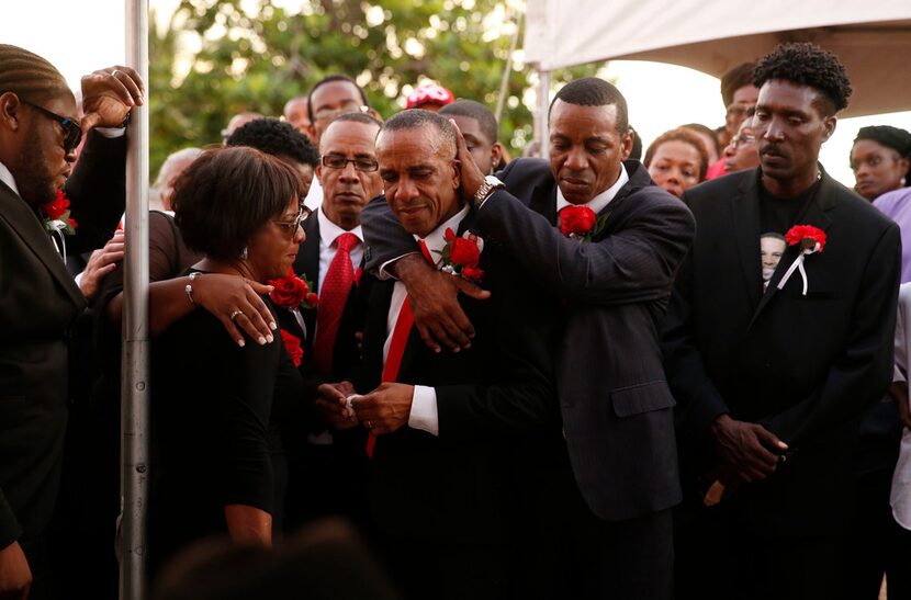 Allison (hidden) and Bertrum Jean hug as they surrounded by family and friends as their son...