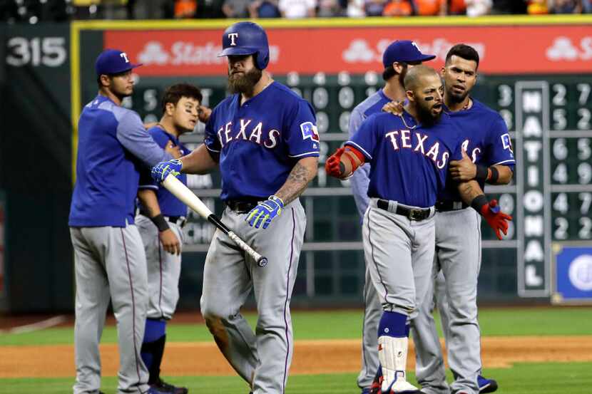 Texas Rangers' Mike Napoli, center, walks away as Rougned Odor, right, is restrained by...