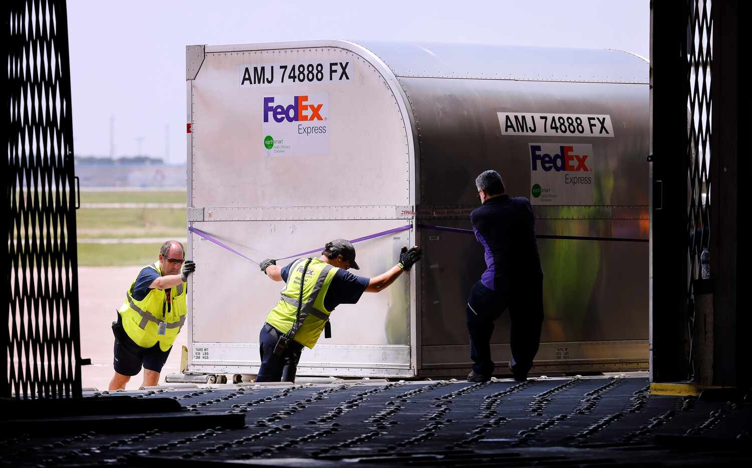 FedEx workers move the first containers of baby formula from an MD-11 charter flight at DFW...