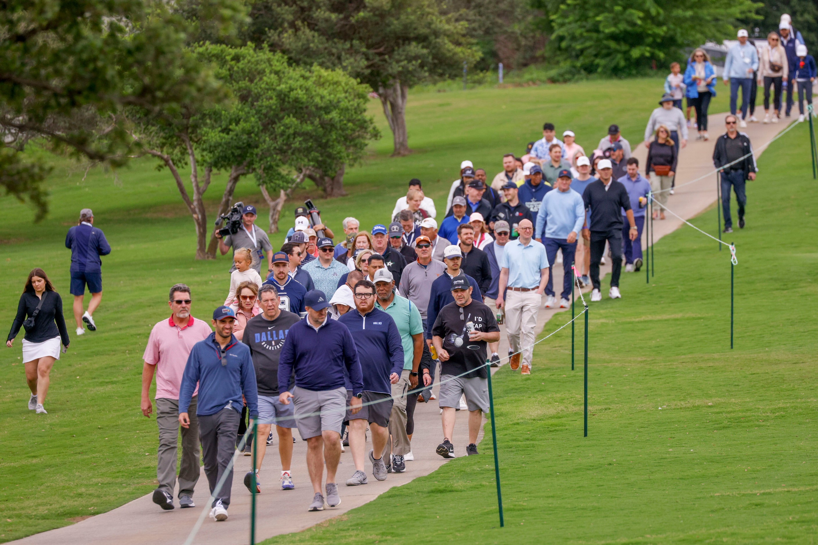 Fans make their way along the ninth fairway as they follow former Dallas Cowboys quarterback...