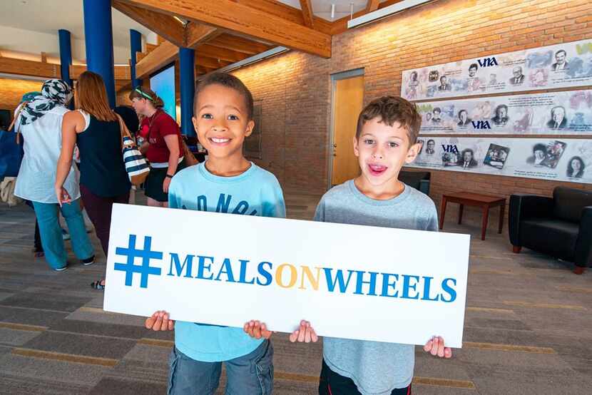 two young boys with a #mealsonwheels sign