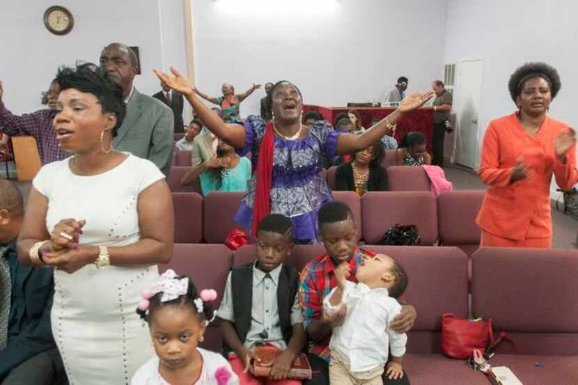
Keabeh Goyah lifted her arms in prayer during a service Sunday at New Life Fellowship...