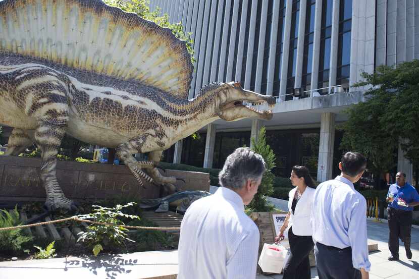 People walk past a full scale replica of the Spinosaurus, the largest predatory dinosaur...