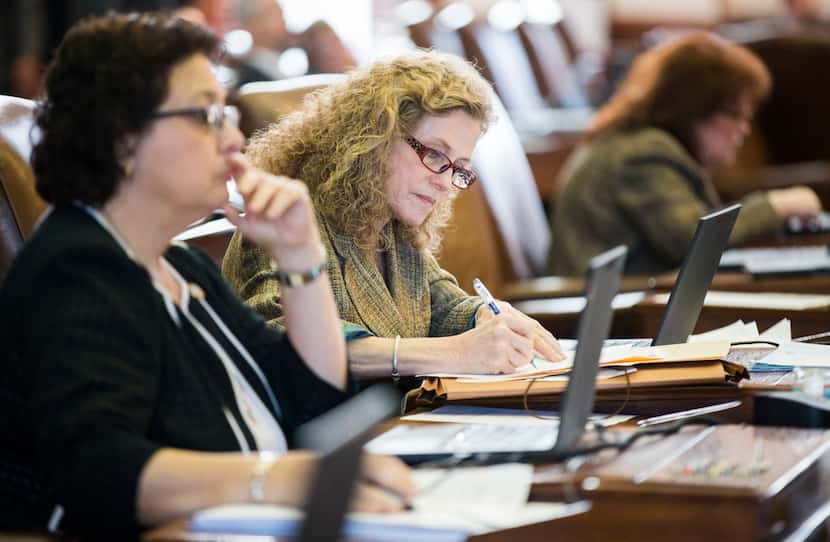 Rep. Donna Howard , right, takes notes at her desk Wednesday as the House took up rules and...
