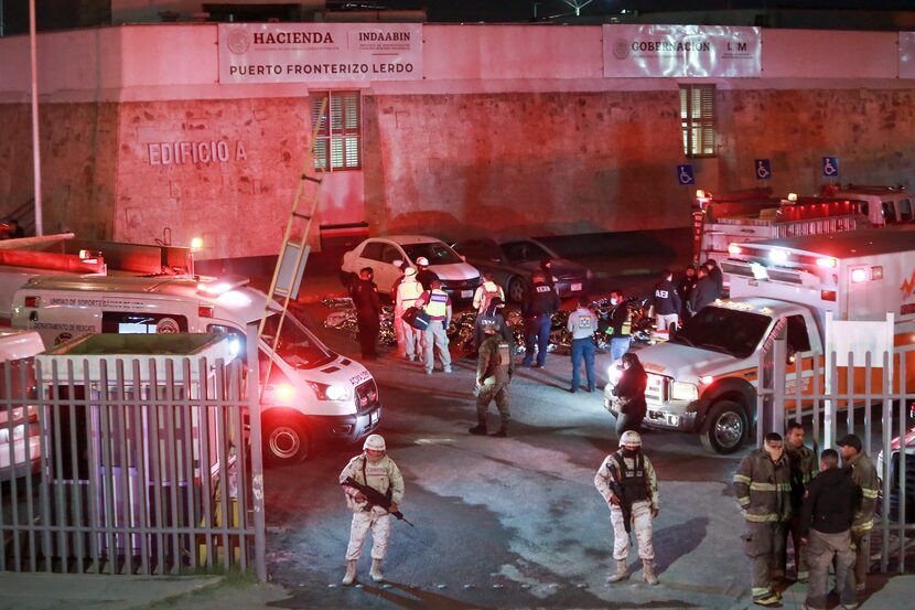 Paramedics and security forces work amid the covered bodies of migrants who died in a fire...