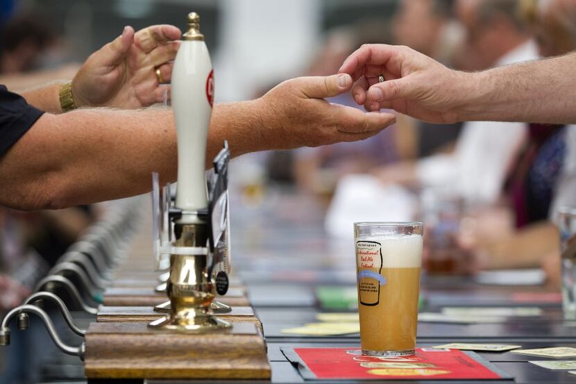 A visitor pays for their drink at a bar during the opening day of the Great British Beer...