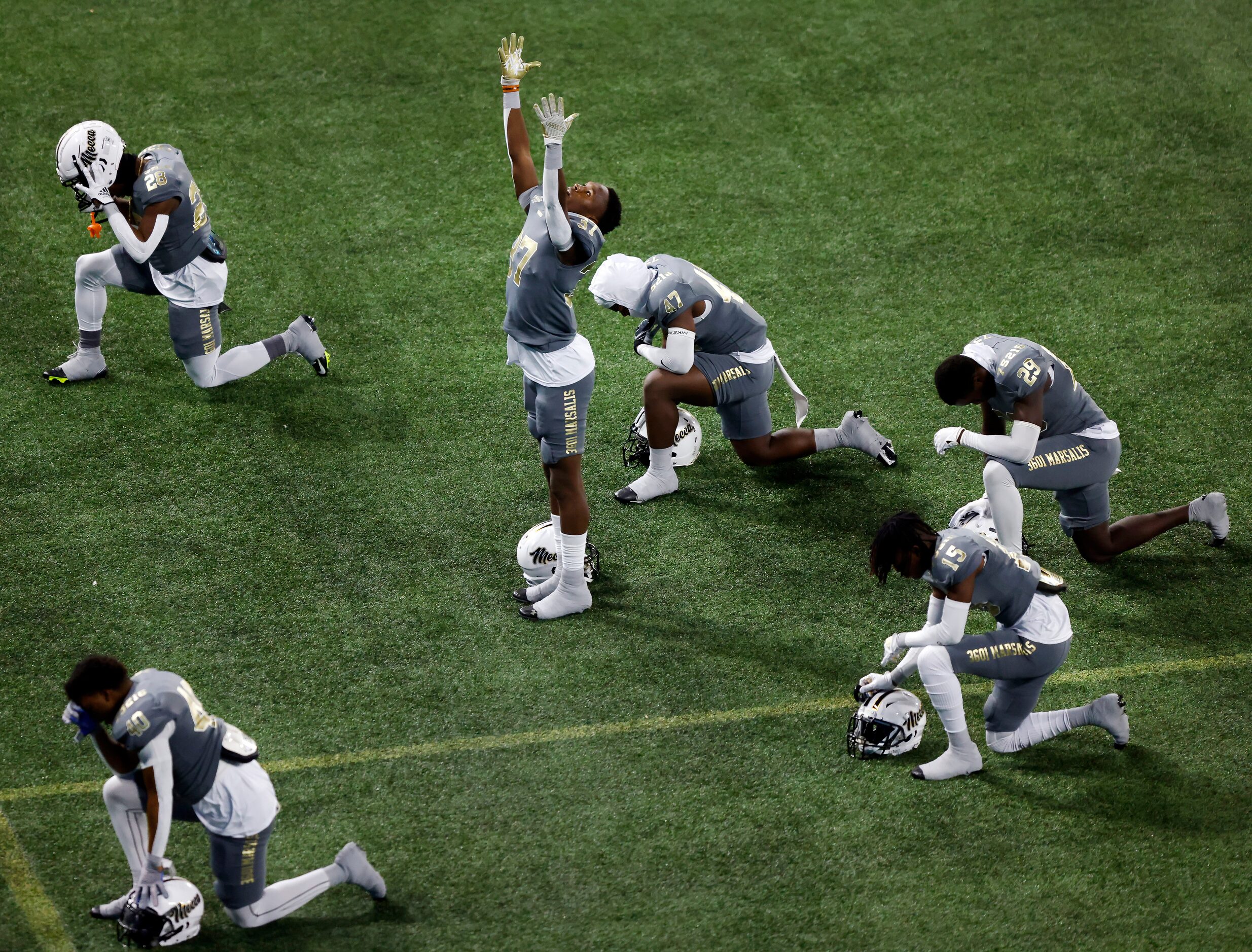 South Oak Cliff’s Dewalon Butler (center) reaches skyward as he and his teammates pray in...