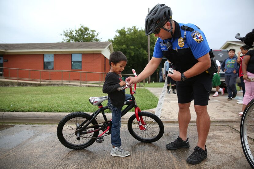 McKinney police Officer Randy Patton gives a sticker to Damian Valencia, 5, while patrolling...