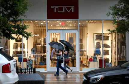 People walked past the Tumi store at Legacy West in Plano during a rain shower Thursday.of 