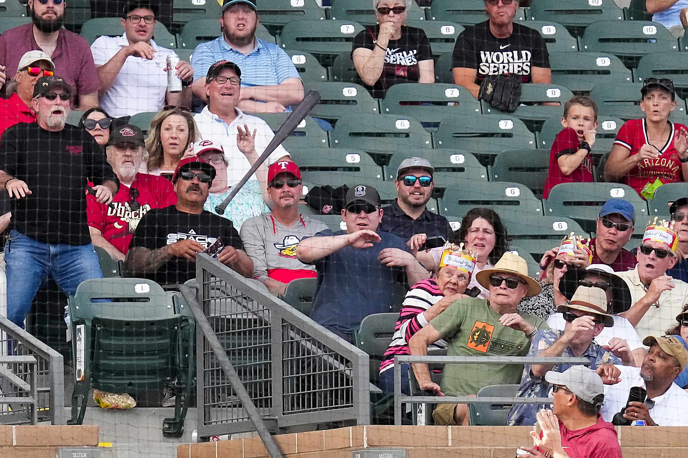 Fans duck away as the bat of Jose Herrera of the Arizona Diamondbacks flies over the net and...