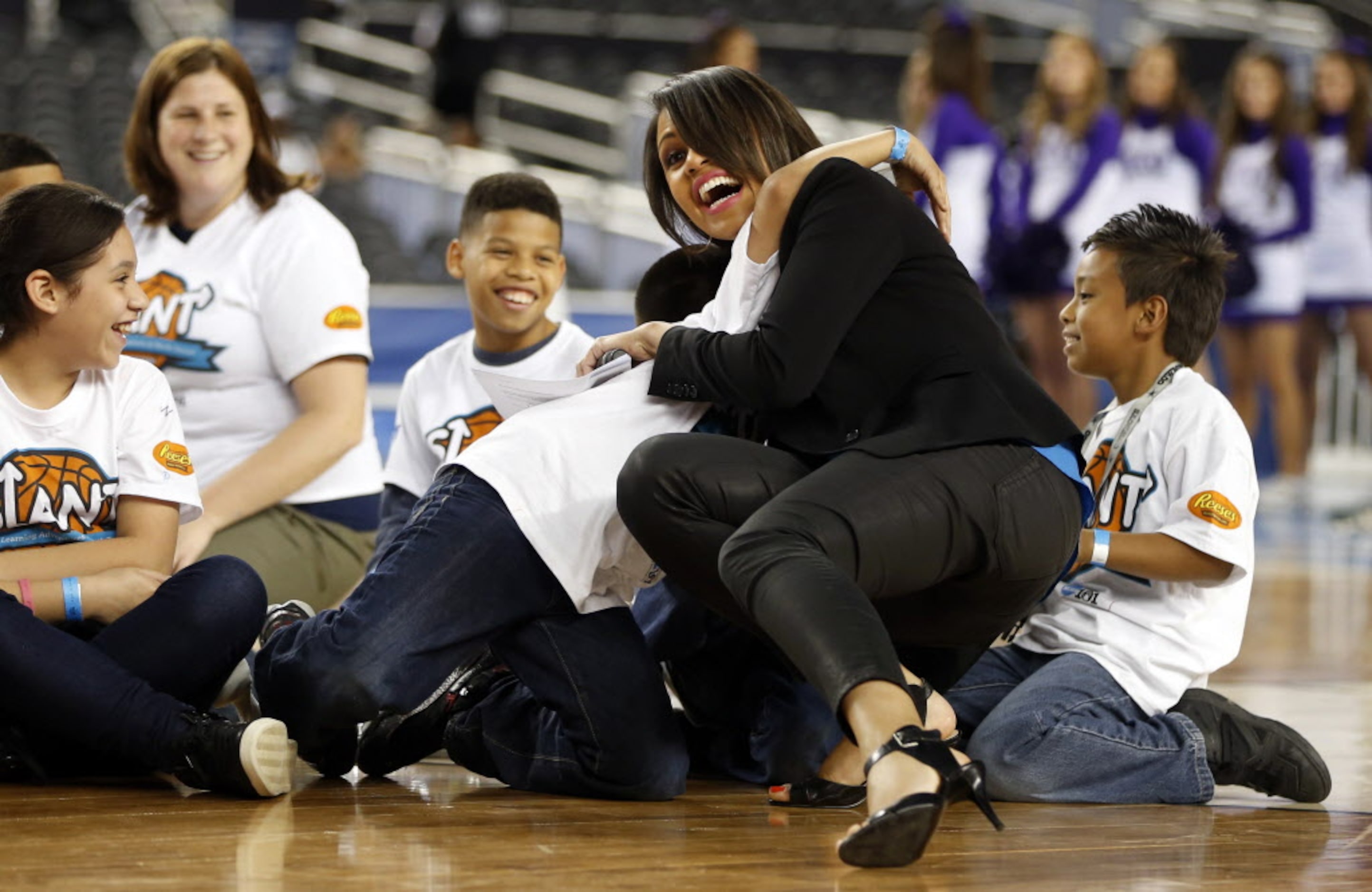 CBS's Adrienne Bankert falls as kids get a hug from her during the Reese's Final Four Slant...