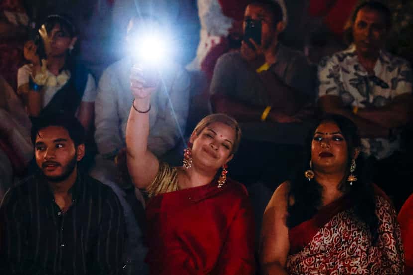 Adiba Mobin (center), waves her cell phone torch as listens to Bangladeshi songs during...