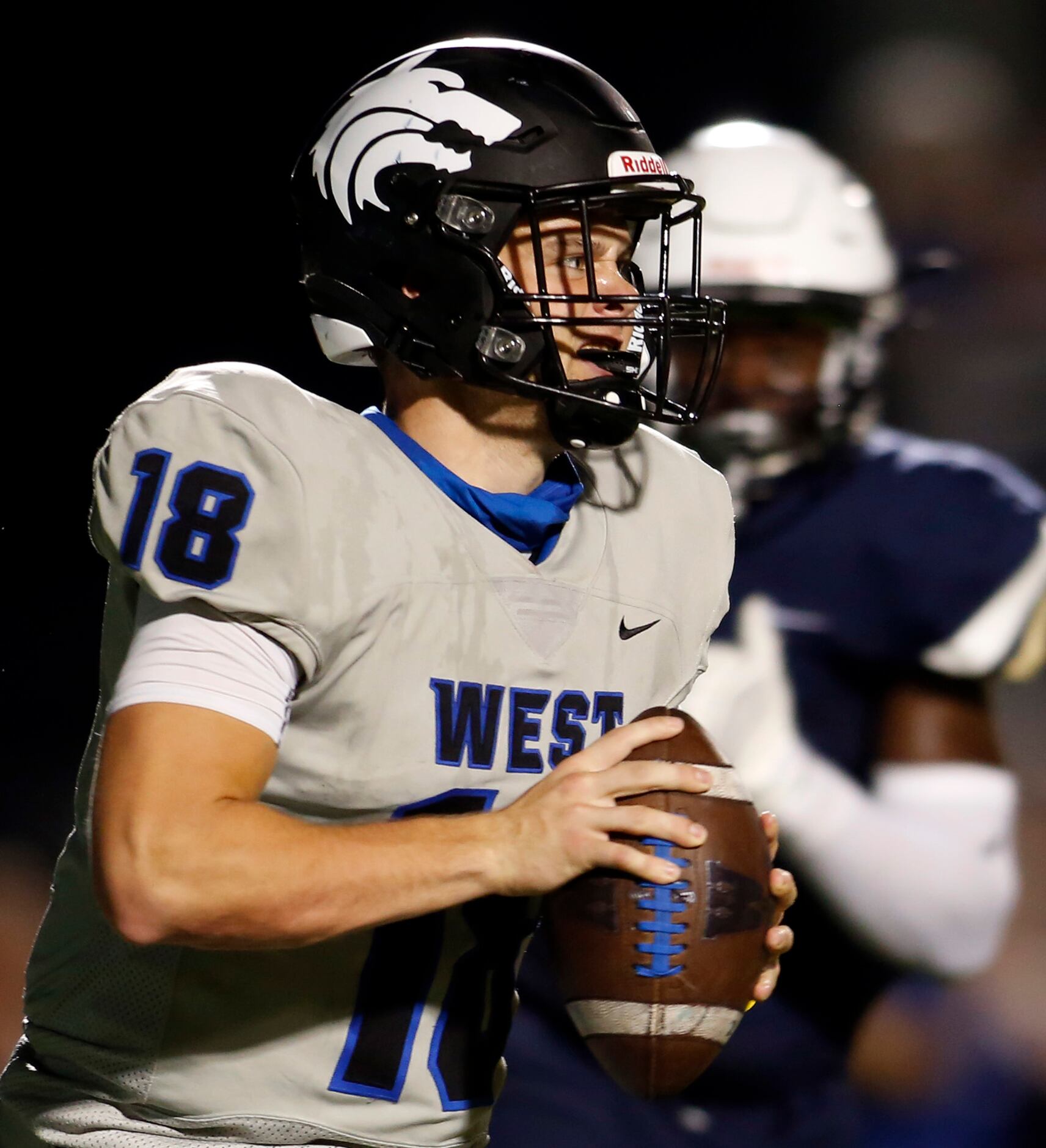 Plano West quarterback Greg Draughn (18) rolls out of the pocket in search of an open...